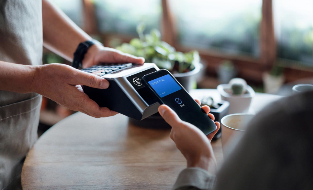 Smartphone displaying Mastercard payment beside a mobile point-of-sale terminal