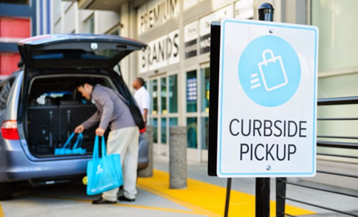 Retail worker loading customer orders into car during curbside pickup