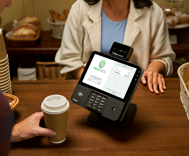 Quick service restaurant crew member using a POS terminal managed by TRG at a busy front counter