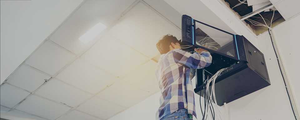Technicien TRG installant un commutateur réseau d’entreprise au plafond d’une installation