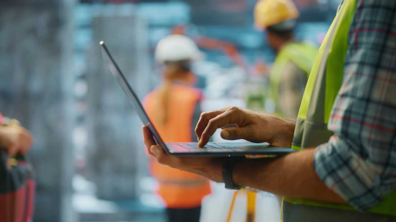 Technician working on a laptop at a jobsite with endpoints managed by TRG