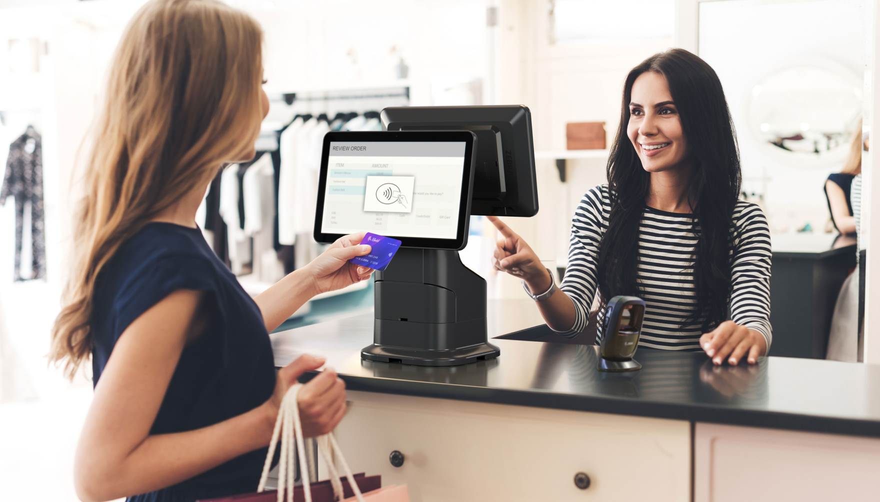 Retail customer tapping card at Zebra KC50 checkout terminal while associate assists.