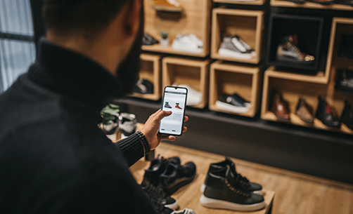 Customer browsing footwear using mobile app in physical shoe store