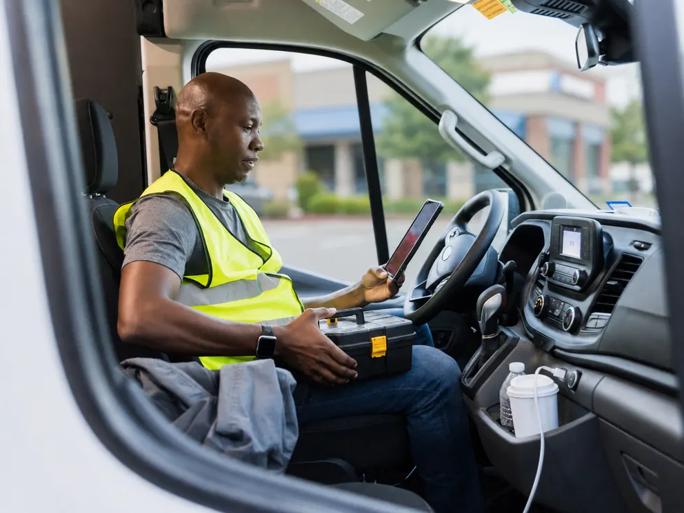 Delivery driver in hi-vis gear using a mobile device in the cab