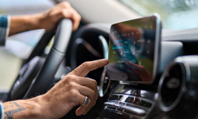 Driver's hand interacting with a car's dashboard screen, showcasing in-vehicle commerce technology.